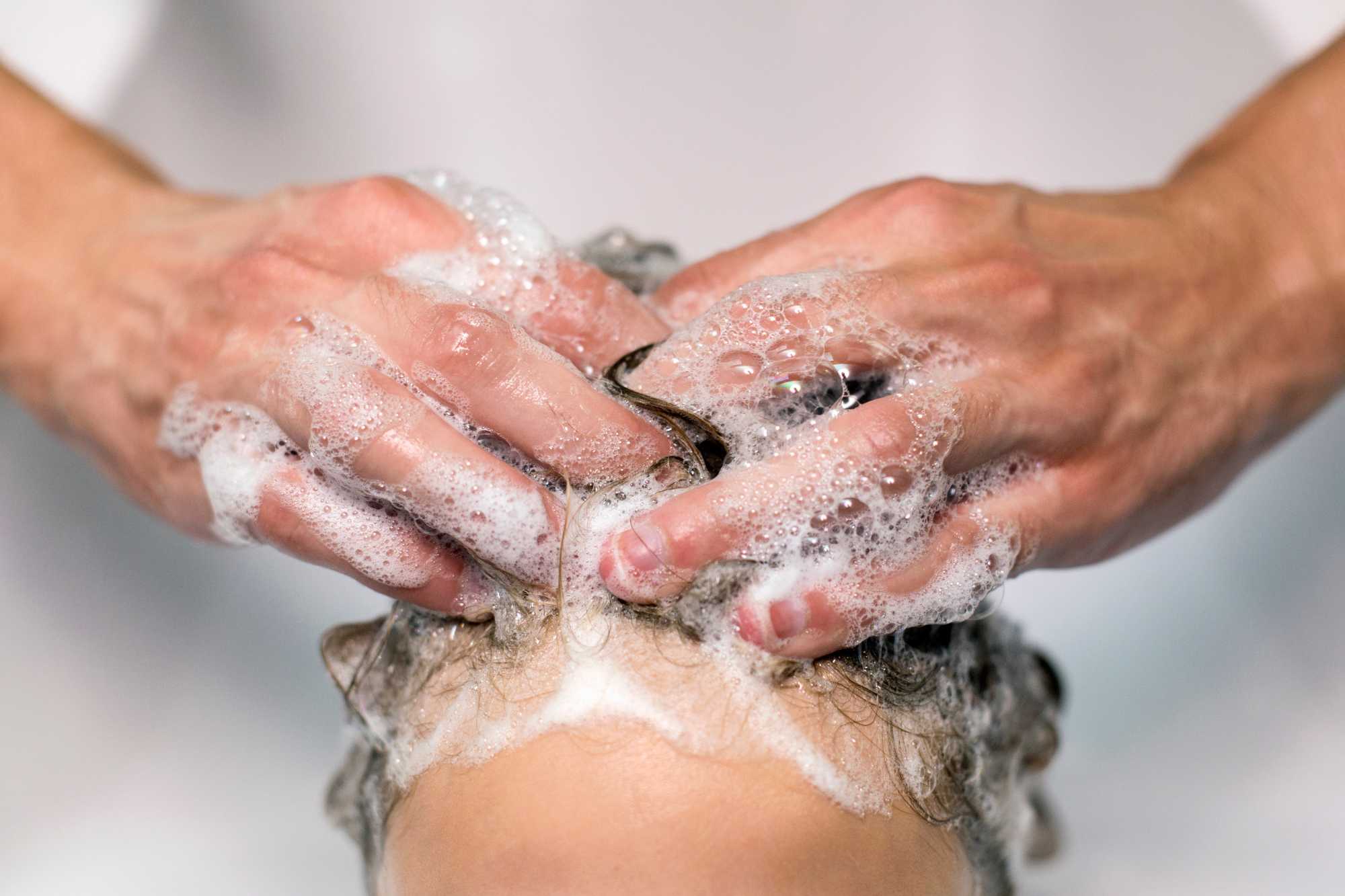 Dospelé ruky umývajú dieťaťu vlasy